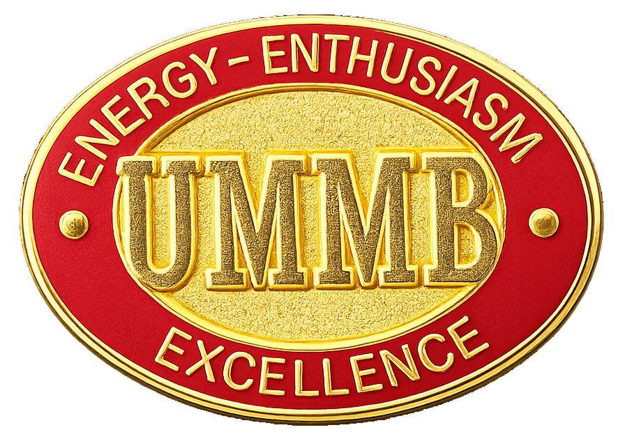 Pin worn on the 2001-2017 uniform. It reads "UMMB" with "energy, enthisuasm, excellence" around the outer band.