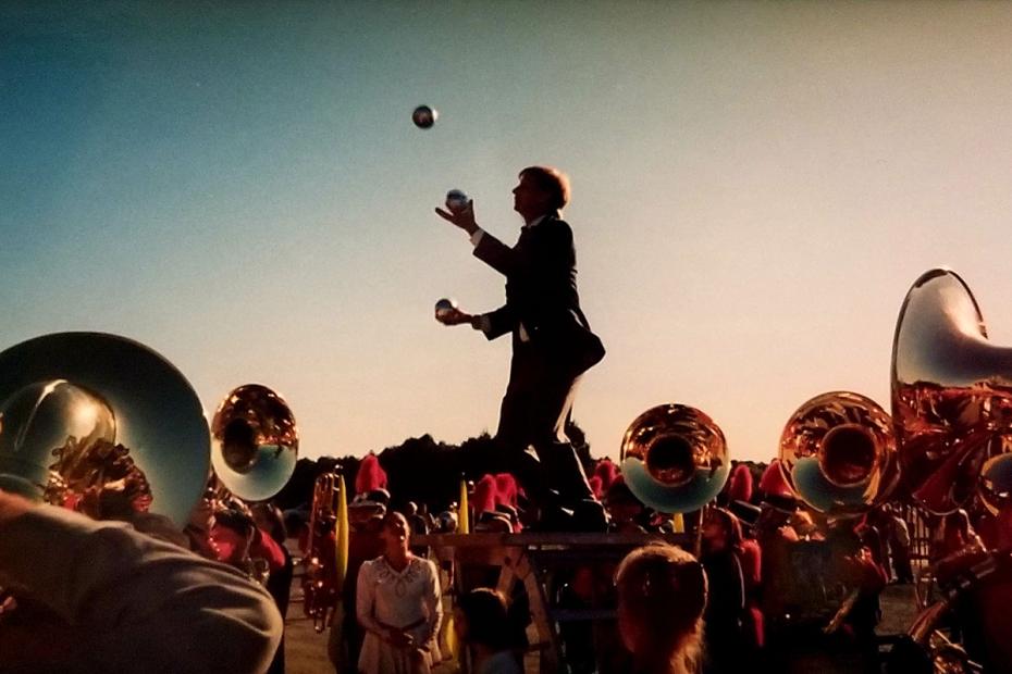 Former band director George Parks juggles balls with the UMass Band watching.