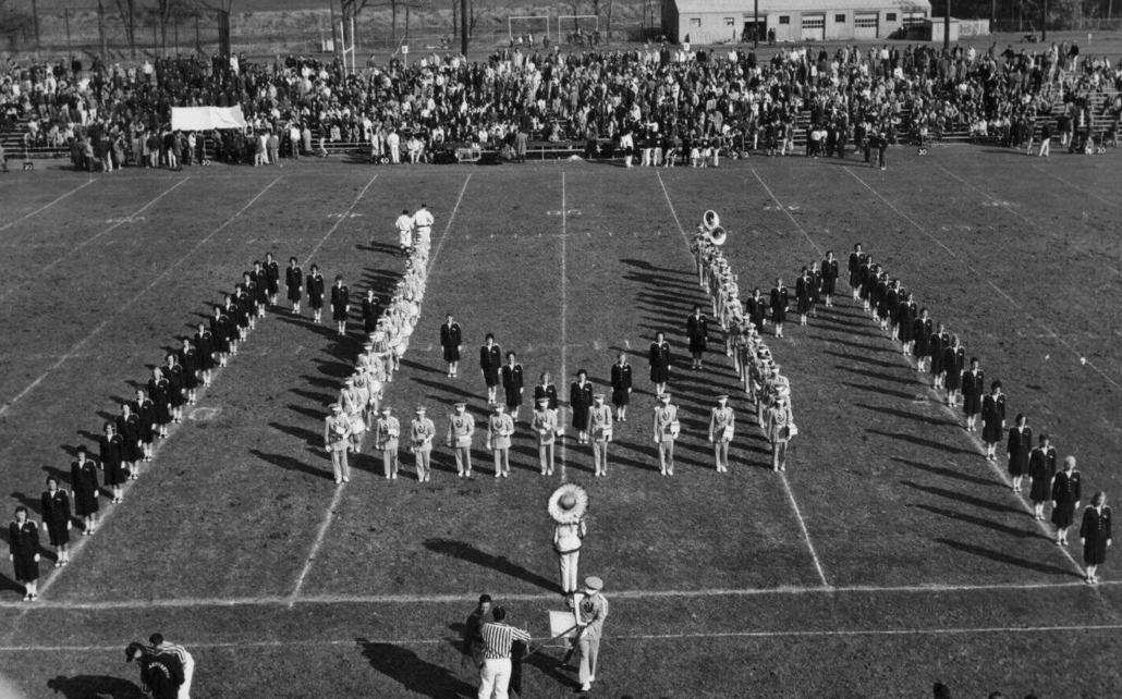 The Precisonettes and the UMass Band form “U-M” at a 1960 halftime performance.